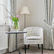 Ein helles Wohnzimmer, das einen Stuhl und eine Vase auf dem Tisch zeigt, ideal für entspannte Momente.