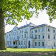 Außenansicht des Klinikums, ein imposantes, weißes Gebäude in einer idyllischen Umgebung.