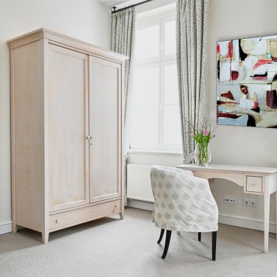 Ein gemütliches Zimmer in der psychosomatischen Klinik mit einem Schreibtisch und einem Stuhl.