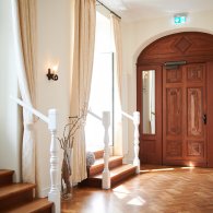 Ein heller Flur mit einer rustikalen Holztür und einem Fenster, das den Raum freundlich erhellt.